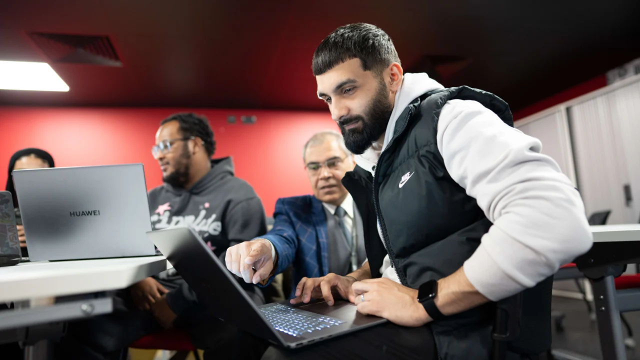 Computer Science students in class on laptop with tutor