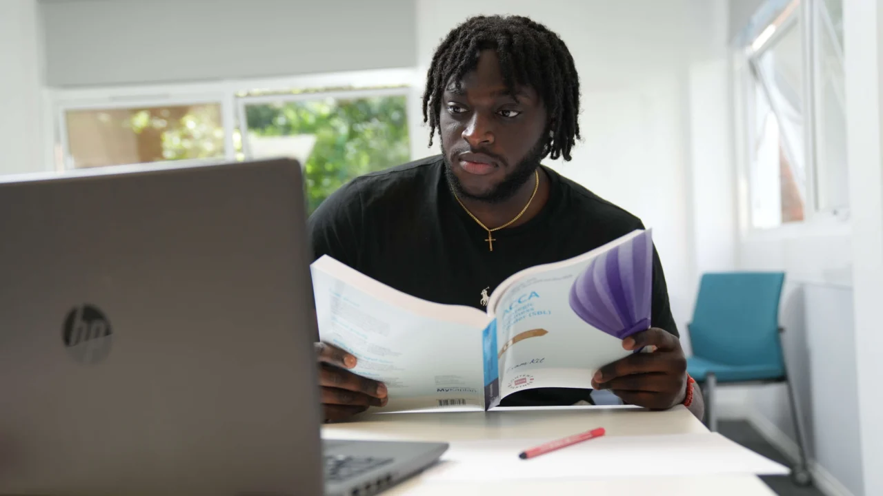 Business student in class with book and laptop