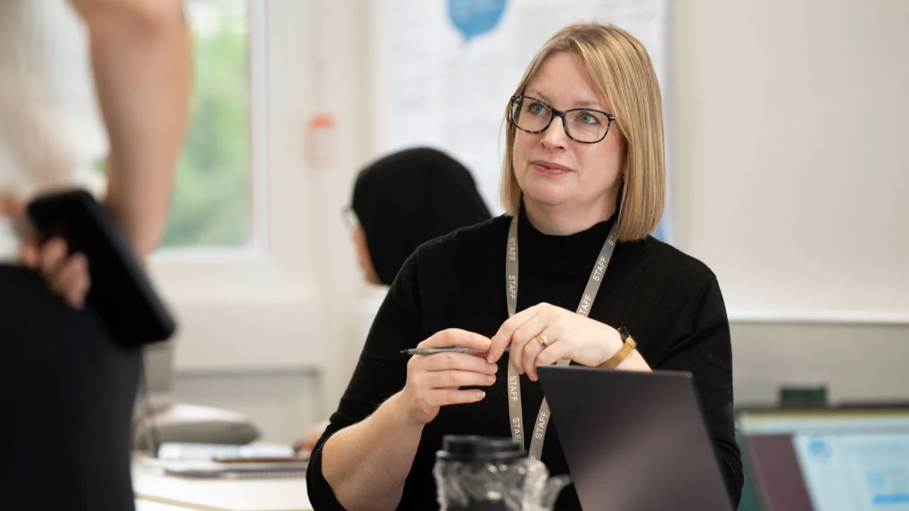 Students engaged in a classroom session, seated in a bright, modern classroom with natural light and discussion materials on the table