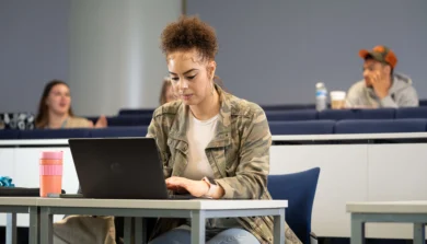 Criminology student in lecture room on laptop