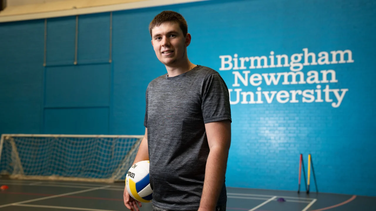 Student in sports hall with ball