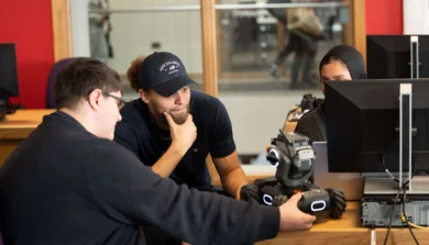Two students in classroom looking at a robot
