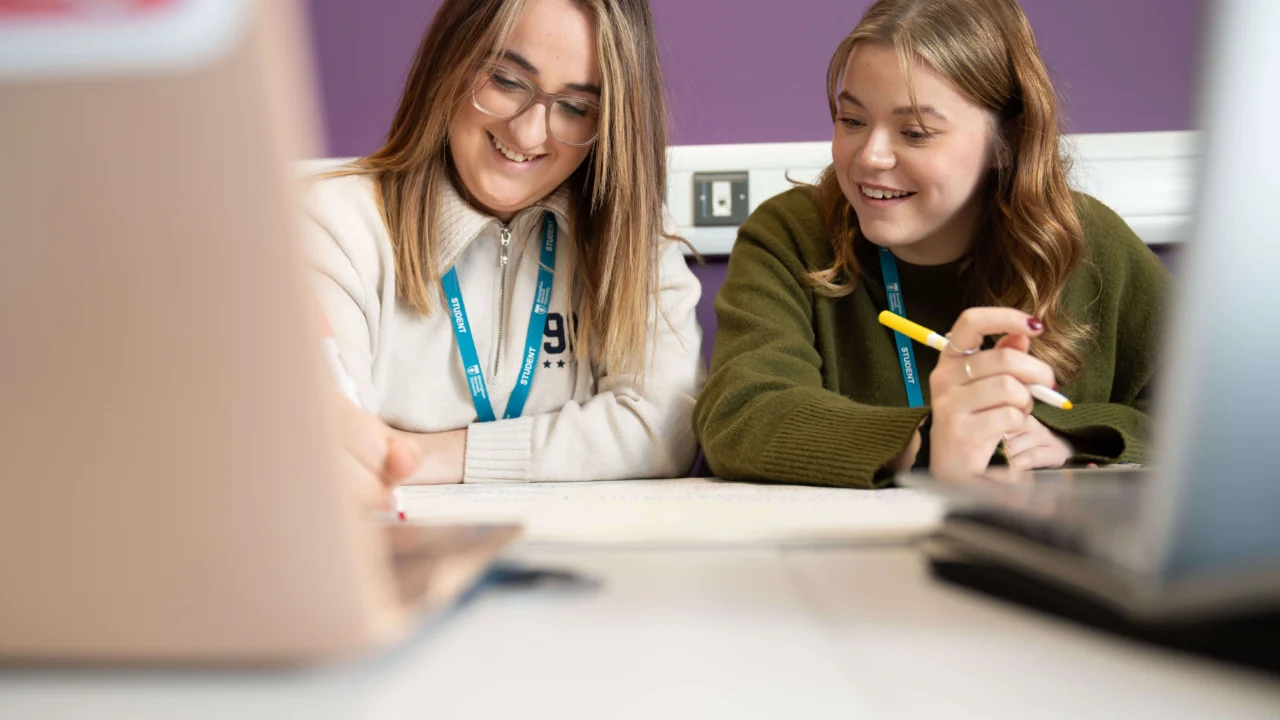 Education students in class talking at table with laptop
