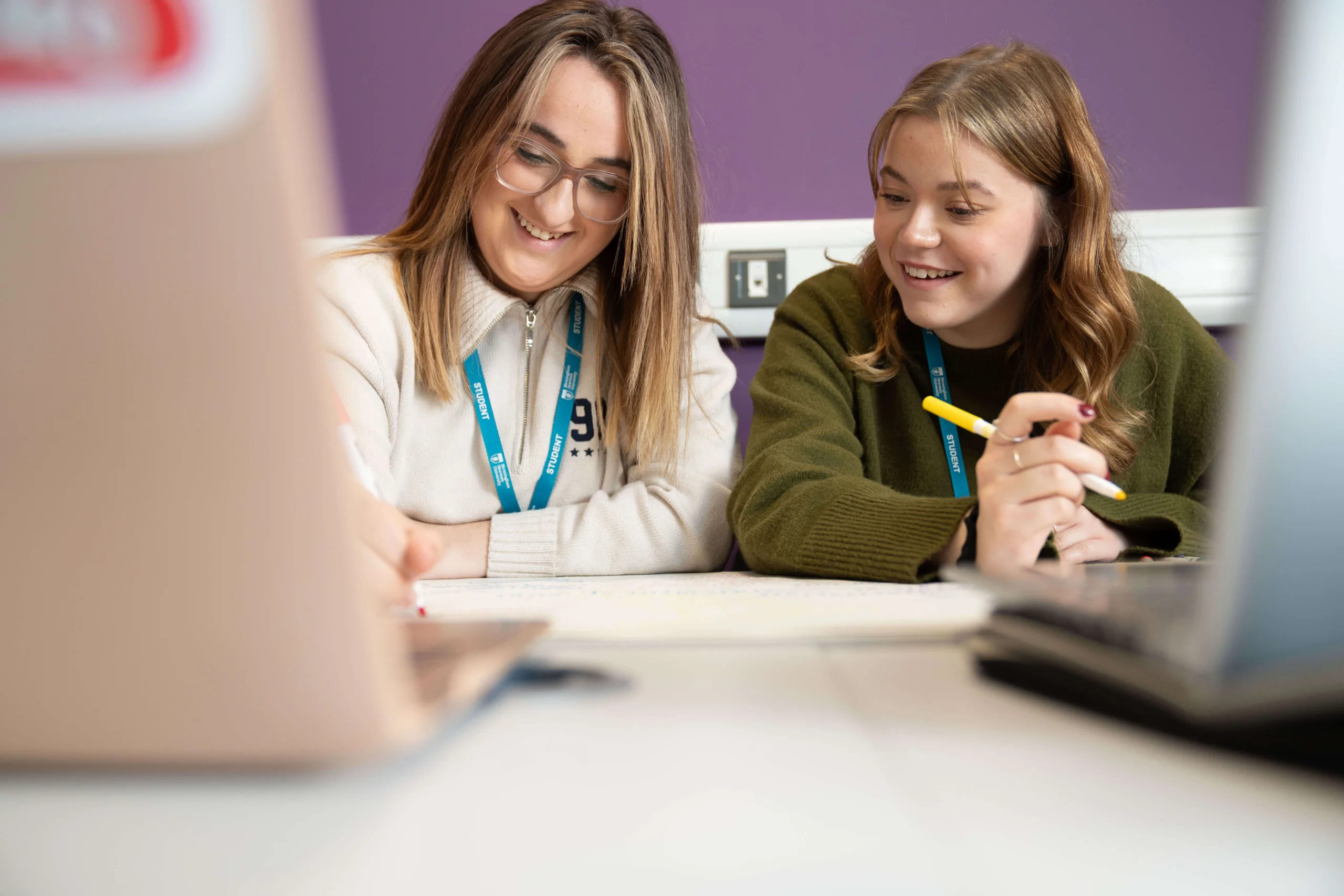 Education students in class talking at table with laptop