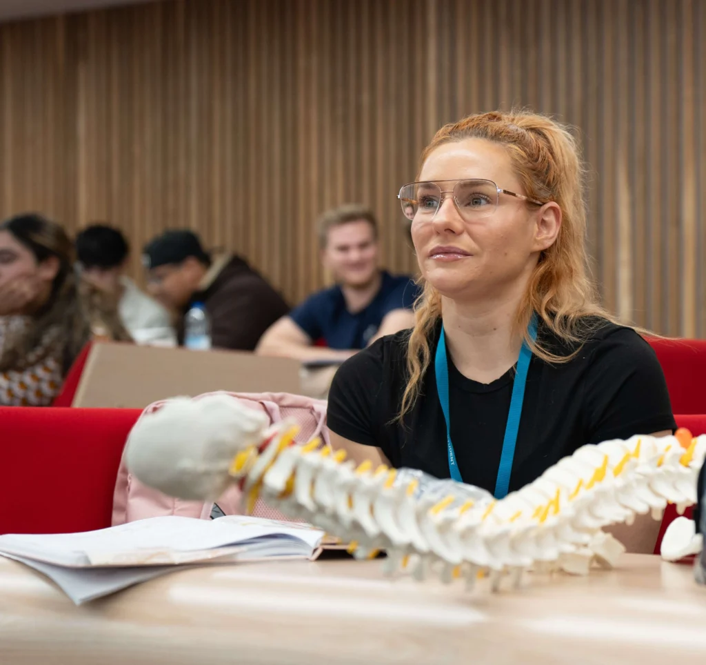 Physiotherapy student in lecture with spine prop