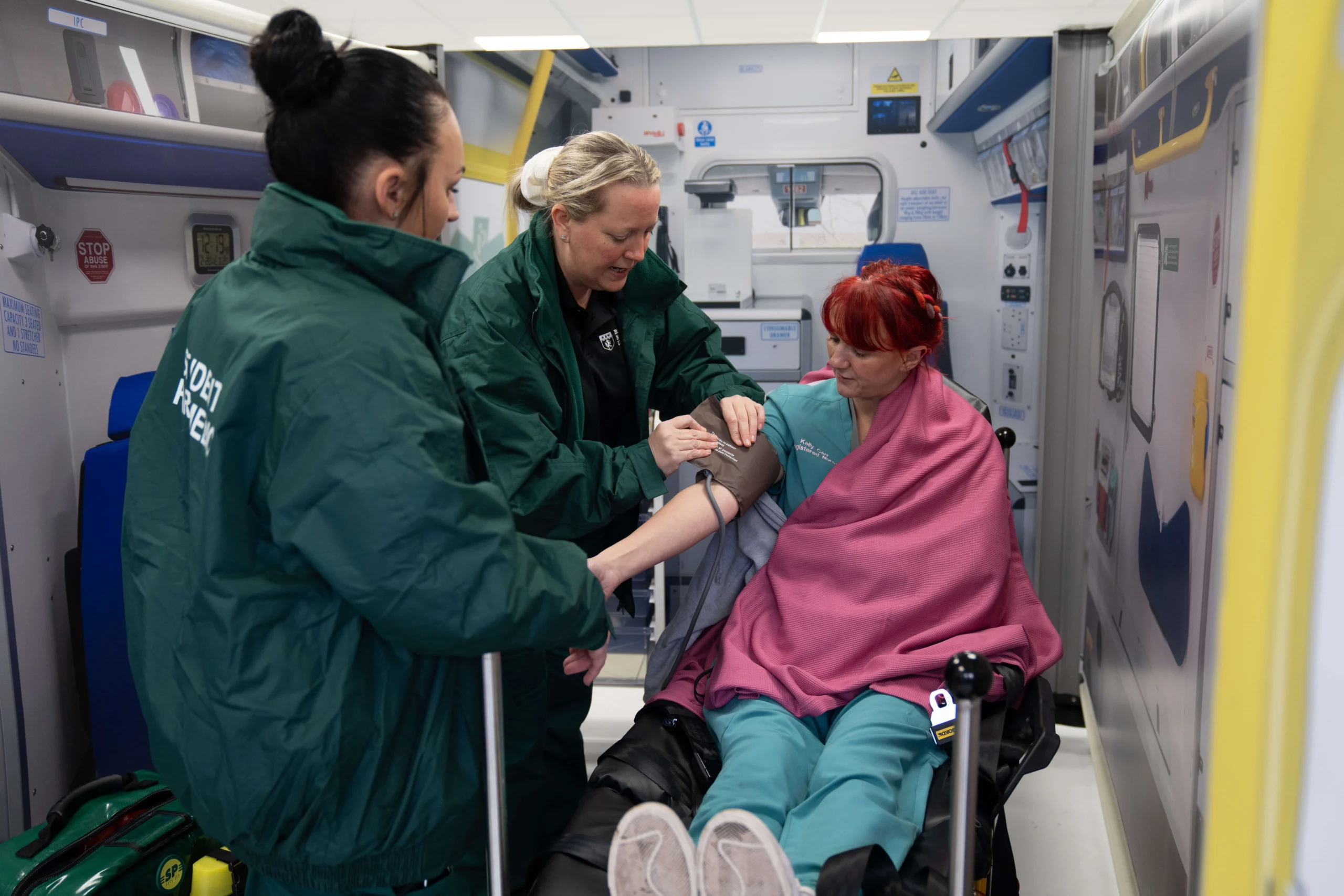 Two paramedic science students in uniform practicing emergency care techniques on a medical manikin in a bright, modern skills lab at Birmingham Newman University.