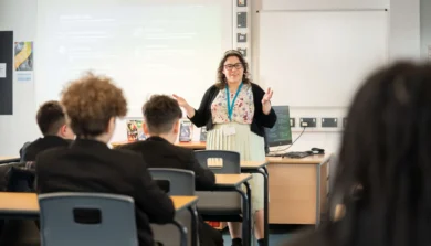 secondary school teacher at front of class talking to students