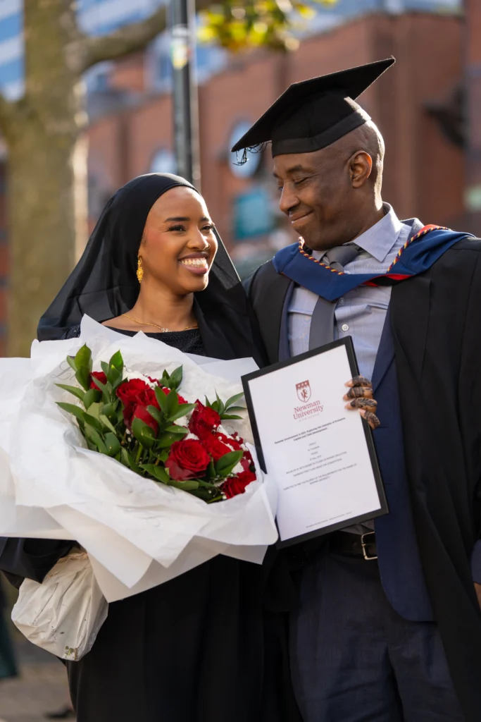 Smiling graduating student celebrating with flowers
