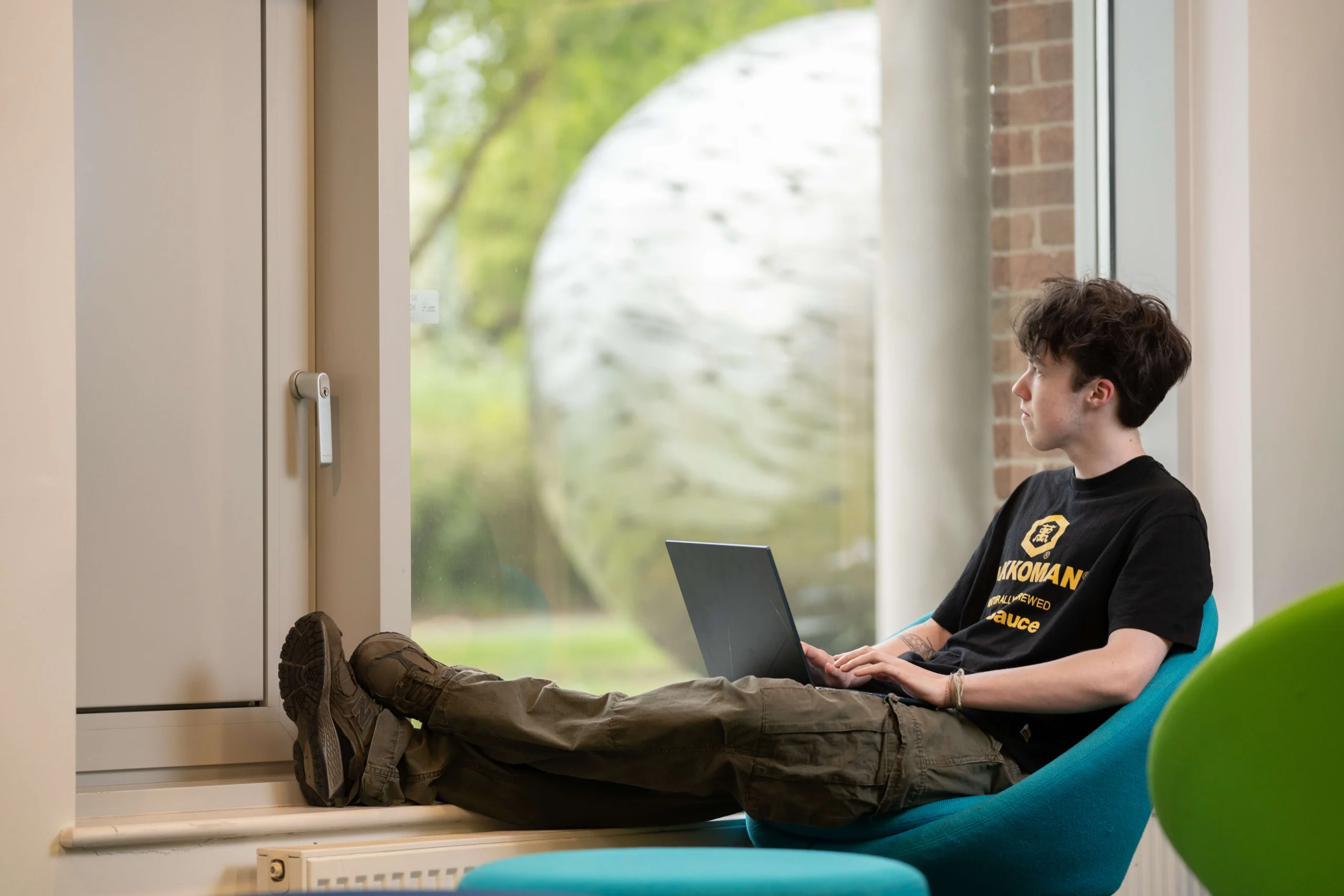 Student in Library on laptop and looking out the window