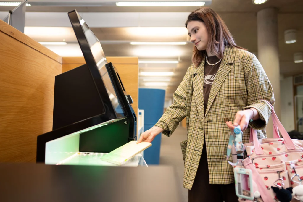 Student scanning a book in the library