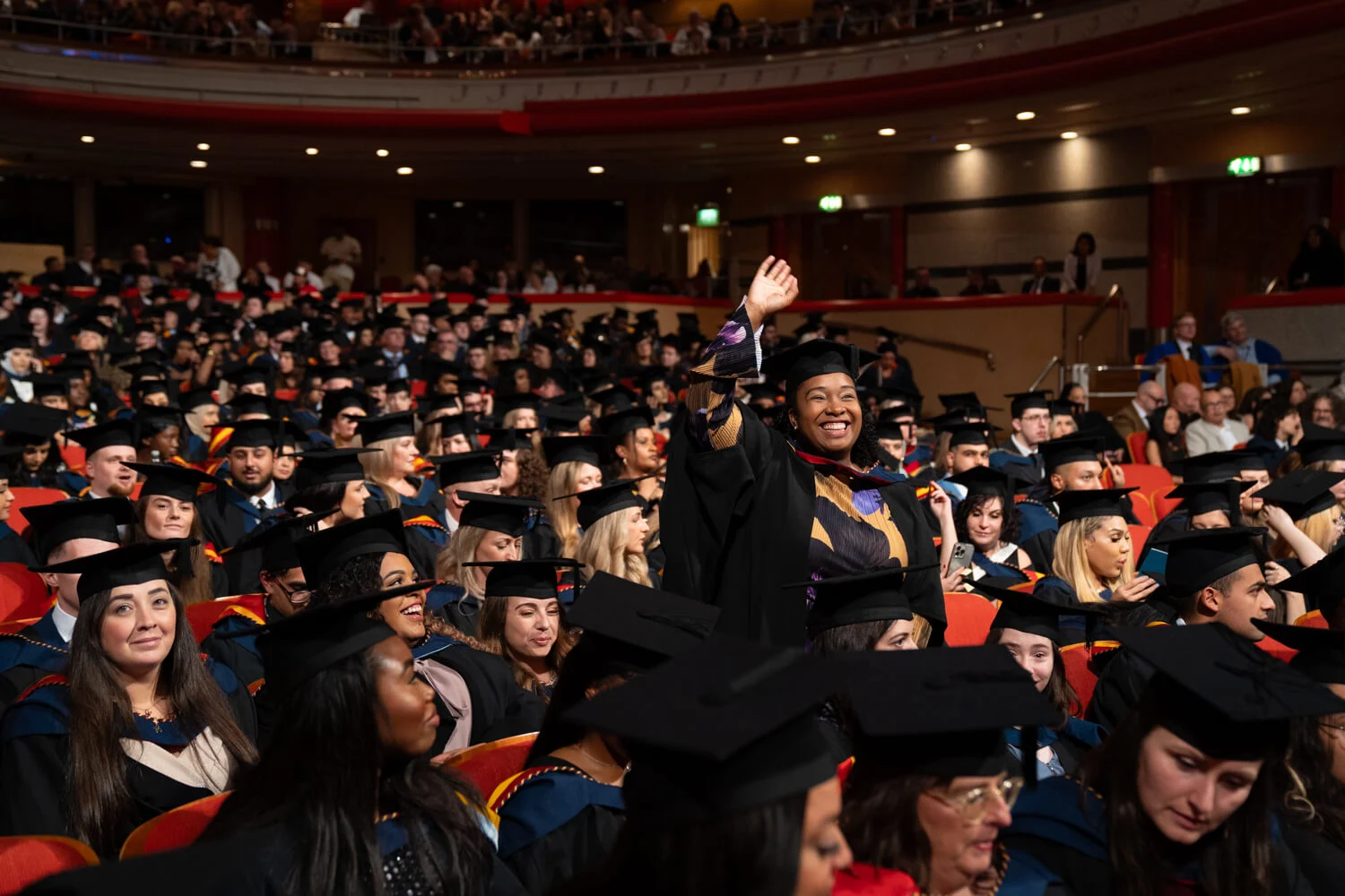 View of audience at graduation with one person standing with hand raised