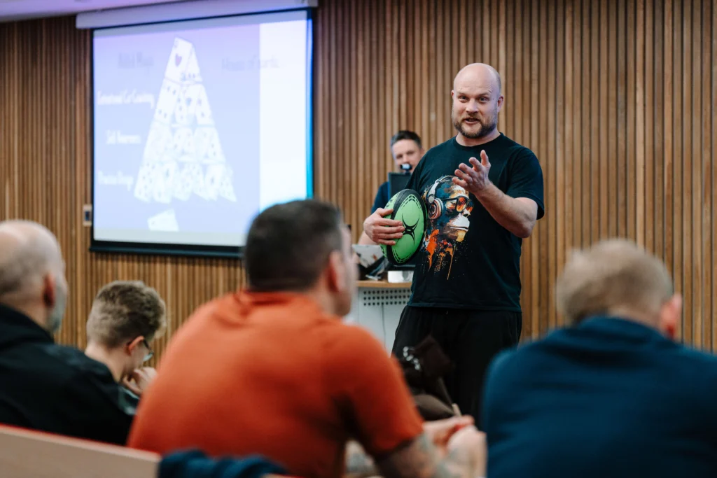 Russell Earnshaw, rugby coach and educator, smiling while wearing a dark jacket and light shirt