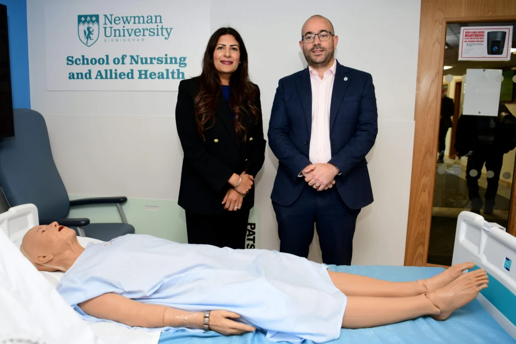 Preet Gill MP and Professor Richard Medcalf in the School of Nursing and Allied Health next to hospital bed and pretend patient on the bed