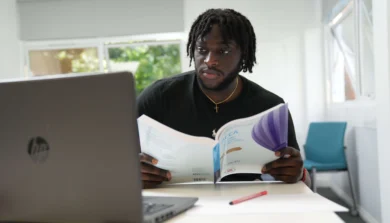 Business student in class with book and laptop