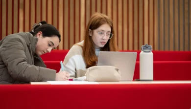 Two students in lecture room on laptop