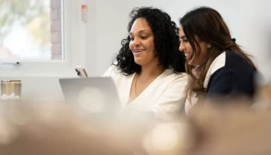 Two students at laptop talking with mobile phone